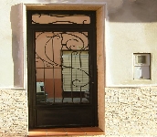Puerta de una hoja con fijo en parte superior adornos trabajados con la fragua de una manera artesanal. Diseño personalizado.Trabajo laborioso y artesanal bien ejecutado.