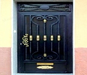 Puerta escalera con barrote trabajado a fragua y adornos de laton.